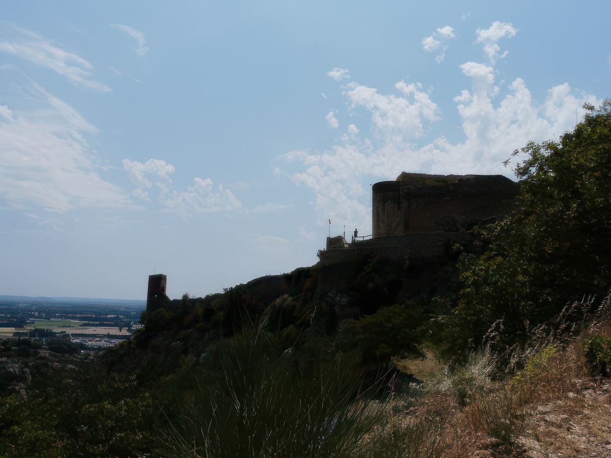 Ses remparts crènelés et sont donjon sont une sentinelle vigilante perchée en haut de la falaise, tous oriflammes au vent.