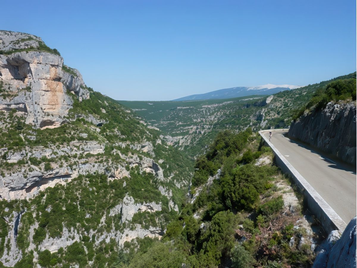 Entre le Rocher du Cire et la route remarquez la cassure provoquée par les gorges, en arrière plan la face sud du Mont Ventoux. Du belvédère des sentiers permettent de descendre dans le fond des gorges. Ce sont parait-il des randonnées pédestres qu'il ne faut pas rater, un spectacle grandiose et vertigineux.