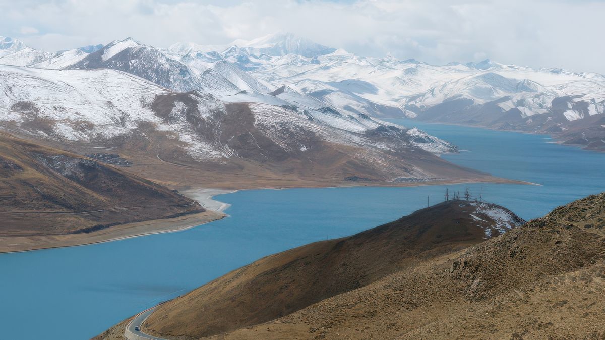 Le Yamdrok-Tso doit la couleur bleue de ses eaux à son origine glacière le Yamdroorigine, au loin se détache le sommet du Norzing Kansar (7 200 m d’altitude).
