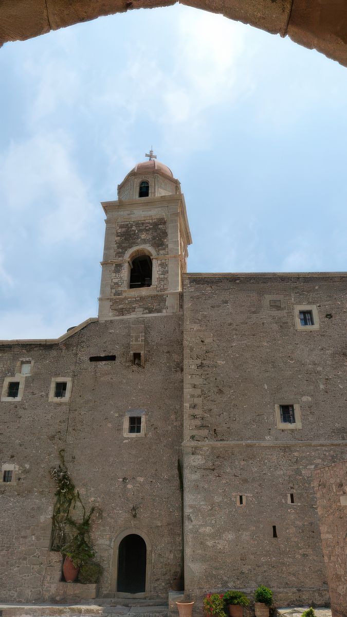 Vue sur l'entrée principale et l'imposant clocher renaissance, haut de 33 mètres. A gauche de la porte, une pierre encastrée dans le mur relate le contrat établi jadis entre les villes antiques d'Itanos et d'Iéraputna.