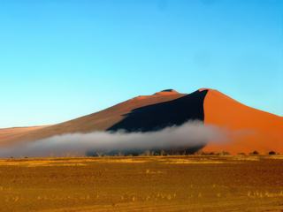 6h00 du mat'. Impressions magiques !! L'humidité de la nuit glaciale s'évapore, formant ainsi des nuages autour des dunes rouges de Sossusvlei. Le Désert de Namib est considéré comme le plus vieux désert du monde. Namibie.