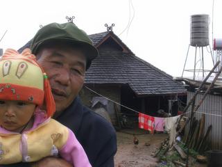 Grand père et sa petite fille dans le village de Bada, en Chine, près de la frontière Birmane. Les différences de génération sont aussi marquées par les vêtements. La petite fille qui vit en ville, est venue rendre visite à son grand père en tenue "Mao"