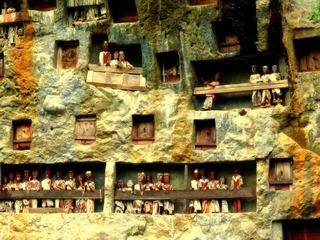 INDONESIE, Ile de Sulawesi. Peut-être pas l'idée que l'on peut se faire d'un cimetière dans notre société, mais là-bas
la culture Toraja repose sur le culte des morts. 
 On peut y voir des cimetières spectaculaires où les demeures funéraires  sont creusées dans les falaises rocheuses. Devant ces tombeaux, se trouvent des balcons avec des effigies mortuaires, les tau tau, qui bénissent les descendants  du défunt en tendant la main en avant. Les tau tau, encore appelés les Morts au balcon, sont sculptés à l'effigie du défunt. Ils sont réservés aux familles nobles.