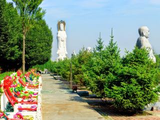 Ce matin, je roule à vélo dans la province chinoise du Xinjiang, à une centaine de kilomètres à l'est de Ürümqi. 
De gros embouteillages se forment à l'entrée d'un parc. Je suis tout d'abord attiré par une immense statue, et d'autres plus petites qui se détachent sur un ciel bleu azur.
         Ce Mercredi 21 août 2013 c'est la Fête des Fantômes affamés. Elle a lieu le 15e jour du septième mois lunaire. Les esprits qui ne reçoivent pas de culte, ou ne peuvent trouver la paix pour cause de mort violente ou de mauvaise conduite, ces "esprits orphelins et fantômes sauvages" se voient offrir ce jour, des repas réconfortants et des cérémonies pour leur délivrance. 
         Les tombes sont toutes couvertes de couronnes de fleurs et d'offrandes. Toute la journée, les familles se succèdent dans le cimetière.
Une halte improbable sur ma route de la soie...