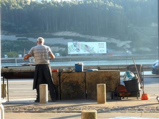 A Porto (Portugal) en pleine ville, sur les quais du fleuve Douro le patron du resto fait grillé des sardines sur le bord de la route malgré le trafic urbain
