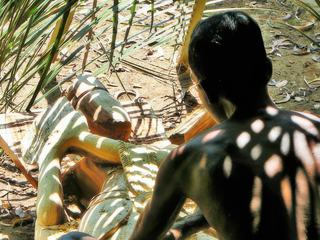Sri Lanka. Photo furtive d'un sculpteur sur bois à l'ombre de branchages entrelacés qui par le jeu de l'ombre et de la lumière dessinent sur son dos une impression de tatouage.