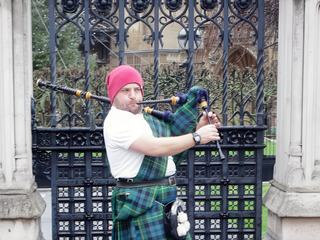Jeune homme jouant de la cornemuse pour quelques livres près de Big Ben à Londres