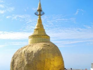 MYANMAR (Birmanie) sur le MONT KYAILKTIYO -  voyage de 2015. On a rendu visite au "ROCHER D'OR"
Cela doit bien tenir d'un petit miracle quand on voit cette image..
En tout cas en voici l'histoire et la légende :
Sur une falaise escarpée à 1 200 mètres altitude  à 4 heures de la capitale RANGOON ce rocher de 8 mètres de hauteur et de 6 mètres de diamètre en équilibre plus qu'instable sur un socle rocheux date de 2 500 ans. Le BOUDDHA aurait fait don d'une mèche de ses  cheveux et l'aurait placée sous le rocher pour le faire tenir en équilibre... et par ce "miracle de la nature" le rocher n'est pas projeté dans le vide et depuis des millénaires tient sur son promontoire...
C'est aujourd'hui l'un des principaux lieux de culte du bouddhisme birman et chaque pèlerin qui le visite le recouvre d'une minuscule feuille d'or (voila pourquoi on l'appelle le rocher d'or).
Autre précision en Birmanie les femmes n'ont pas le droit de le toucher ni de s'en approcher.
En tout cas c'est un lieu incontournable lors d'un séjour au MYANMAR et c'est poignant de voir les fidèles religieux comme laïques honorant ce lieu naturel  mystique et miraculeux pour eux en priant et déposant une minuscule feuille d'or qui pourtant pour beaucoup d'entre eux représente une petite fortune, mais pour les Birmans un miracle n'a pas de prix.