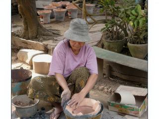 Une tâche qui revient aux femmes: isoler la poterie des rebords du seau pour la cuisson au four.