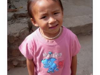 Une petite fille très coquette, son collier de perles au cou.