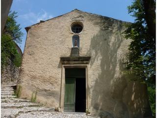 Au pied d'une calade, belle de simplicité, la façade et le porche d'entrée de l'église saint Sidoine.