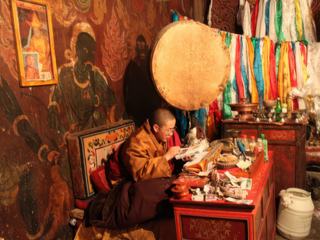 Monastère de Pelkor Chode. Un moine a prit mon routard et regarde les photos esperant y voir le Dalaï-lama