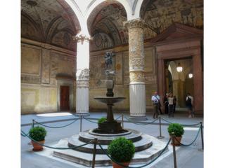 La première cour (cortile) du Palazzo Vecchio à laquelle on accède par la porte principale depuis la Piazza della Signoria, fut projetée en 1453 par Michelozzo. En 1565, à l'occasion des noces de François ler de Médicis, fils de Cosme Ier, et Jeanne d'Autriche, la cour fut transformée et ornée dans un style maniériste exubérant sur un projet de Giorgio Vasari. Au centre, fontaine en porphyre, sur laquelle fut placée la plus ancienne statue en bronze du Putto con delfino d'Andrea del Verrocchio (1476).