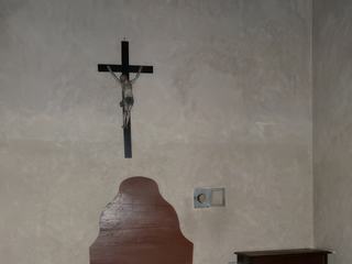 La chambre à coucher occupée par un lit de bois simple, une table de nuit et un prie-dieu.