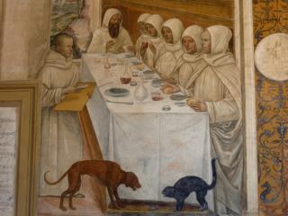 Benoît obtient de la farine en abondance et restaure les moines Remarquez le sourire du serveur qui s'aperçoit qu'un moine met la main sur le petit pain du voisin. Notez aussi le chat et le chien qui se disoputent la tête d'un poisson.