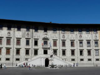 Le palazzo della Carovana fut construit par Vasari entre 1562 et 1564. Il doit son nom aux chevaliers de Santo Stefano, un ordre de moines-soldats, fondé en 1561-1562 par Cosme Ier de Médicis pour combattre les Turcs et les Infidèles. Sa façade a été réalisée selon la technique du sgraffito, succession de motifs blancs sur fond gris foncé, qui représentent des signes du zodiaque et les vertus civiles, religieuses et militaires du grand duc. L'ensemble a été complété par des bustes des grands-ducs de Toscane, réalisés entre 1588 et 1718, dans des niches sous les fenêtres du dernier étage. En 1821, on ajouta au palais un double escalier néoclassique. En 1847, il devint le siège de la Scuola Normale Superiore, fondée en 1810 par Napoléon Ier. La plupart des édifices de la piazza dei Cavalieri appartiennent aujourd'hui à cette école.