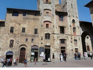 Au 1er plan, les 2 tours jumelles des Ardinghelli se situent sur la place de la Cisterna, à l'angle de la place du Duomo. Les Ardinghelli (guelfes), l'une des puissantes familles de San Gimignano, à l'instar de la famille rivale des Salvucci (gibelins), avaient fait ériger ces 2 tours qui s'élevaient plus haut que la tour du Podestà (la tour Rognosa), ce qui enfreignait la règlementation en vigueur dans la commune. Tout comme les Salvucci, les Ardinghelli entendaient ainsi montrer leur puissance et leur suprématie sur la ville. A l'arrière plan, la Tour Grossa.