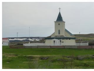 La petite église verte et blanche de Reykjahlíð (rebâtie en 1972), située sur la rive Nord du lac Mývatn, au pied du volcan Krafla. Le volcan a toujours représenté une menace pour le village depuis l'établissement des premières fermes. Reykjahlíð fut en partie rasé par la fameuse coulée de lave de 1729 (les Feux de Mývatn), l'église étant le principal bâtiment épargné. Celle-ci se situait en effet sur la trajectoire de la coulée de lave qui, au moment d'atteindre sa porte, se scinda en 2 et contourna l'édifice en bois. Les fidèles ne manquèrent pas d'y voir l'intervention de Dieu.