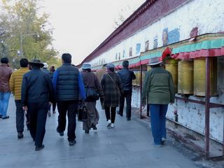 Au dessus des moulins de prières on peut voir des mantras peints sur le long mur blanc.
