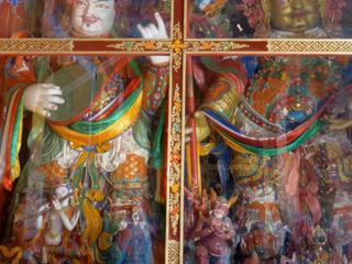 De chaque côté de la porte d'entrée les Gardiens du Monde appelés aussi "Lokapalas" (2 sur chaque côté). Ici, Dhritarastra, de couleur blanche (pureté) et Vaishravana, le chef des Lokapalas. Ce sont les quatre grands rois présidant aux quatre coins du monde et aux quatre saisons. Ils sont avant tout "protecteurs", et leur première tâche est de garder le Bouddha, puis le monde, de l'invasion des démons. On les trouve souvent à l'entrée du "Dukkang" salle d'assemblée et de prières dans les monastères. Toujours représentés debout, avec une allure martiale, ils portent souvent des armures ou sont en tenue de combat, comme tous les gardiens.