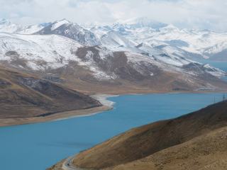 Le Yamdrok-Tso doit la couleur bleue de ses eaux à son origine glacière le Yamdroorigine, au loin se détache le sommet du Norzing Kansar (7 200 m d’altitude).