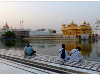 Remarquez les 2 drapeaux à gauche, il s'agit du Nishan Sahib, le nom du drapeau sikh qui est placé au-dessus des gurdwaras, les temples sikhs, et les autres lieux religieux importants dans le sikhisme. Nishan vient du perse et veut dire drapeau, sahib vient de l'arabe et se traduit par "maître", "seigneur"; c'est un titre honorifique souvent utilisé dans le sikhisme comme dans le nom du Livre saint : le Guru Granth Sahib. Le drapeau sikh est triangulaire, souvent orange, safran, quelquefois bleu avec le symbole du sikhisme: le Khanda. L'épée à double tranchant qui est au centre du drapeau se dénomme aussi khanda. Un disque dénommé chakra représente le centre, il est le symbole de l'unité; deux poignards, des kirpans, l'entourent. Le kirpan fait partie de la tenue traditionnelle du sikh et s'inscrit dans la règle des Cinq K.