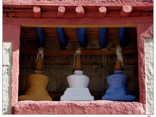 Trois jolis petits chörtens colorés sont exposés dans la cour: le jaune pour la sagesse, le blanc pour la compassion et le bleu pour la protection.