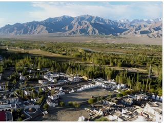 Vue sur la vallée verte de l'Indus, parmi les vergers et les champs d'orge, l'aridité des montagnes et quelques sommets enneigés en arrière plan.
