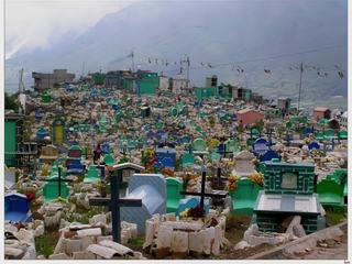 Le cimetière maya de Zunil qui surplombe le village fait face au volcan Santa Maria (3.772m), invisible ce jour-là à cause de la brume. Très coloré, le vert prédomine car cette couleur symbolise l'espérance du paradis. Sur le côté on peut voir des cerfs-volants restés accrochés aux fils électriques. Les Mayas ont adapté la fête de la Toussaint, fête catholique, à leur culte des morts. Ils viennent fleurir les tombes dans une ambiance joyeuse et pour communiquer avec eux ils utilisent des cerfs-volants qui les relient à l'âme des défunts.