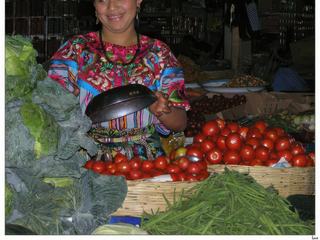 Le beau sourire de la vendeuse de tomates, haricots verts, choux, etc... A l'arrière, une épicerie.