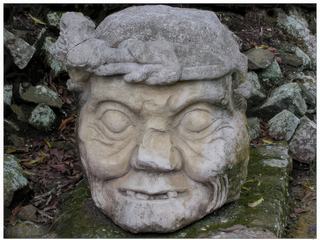 Tête d'un pauahtun ou bacab, l'un des quatre dieux associés aux quatre points cardinaux. Cette sculpture est située dans le coin nord-est de la structure 11 de l'Acropole. L'original est au Musée de la Sculpure Maya pour être protégé des intempéries.