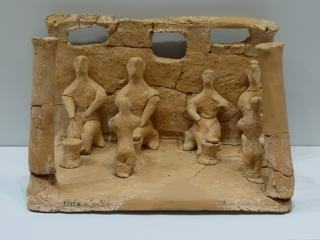 Cette poterie, réalisée en terre cuite,provient de Phaestos, elle est datée 1600 av J.-C. Scène d’offrandes dans un sanctuaire domestique, peut-être adressée à un ancêtre décédé.