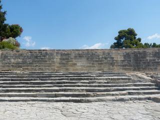 La cour ouest avec les gradins du théâtre qui montent vers un mur aveugle. Il date de l'époque de l'ancien palais qui était protégé sous 1,3 m de la nouvelle construction. D'une longueur de 22 mètres, il surplombe un vaste espace dallé qui est une voie de procession. A ce jour les archéologues n'ont toujours pas pu déterminer quels types de spectacles ou de cérémonies auxquels assistaient les spectateurs de l'époque.
