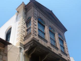 Au dessus d'une boutique une façade de maison ottomane, reconnaissable à son balcon en bois.